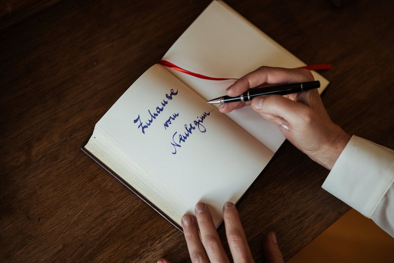 Gabriella Rist schreibt „Zuhause vom Neubeginn“ mit dem Füller in ein aufgeschlagenes Buch